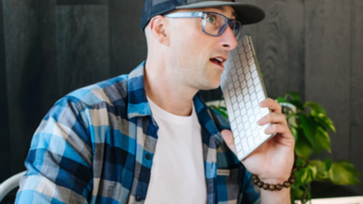 Steve holding a keyboard up to his ear like a phone, mid-laugh.