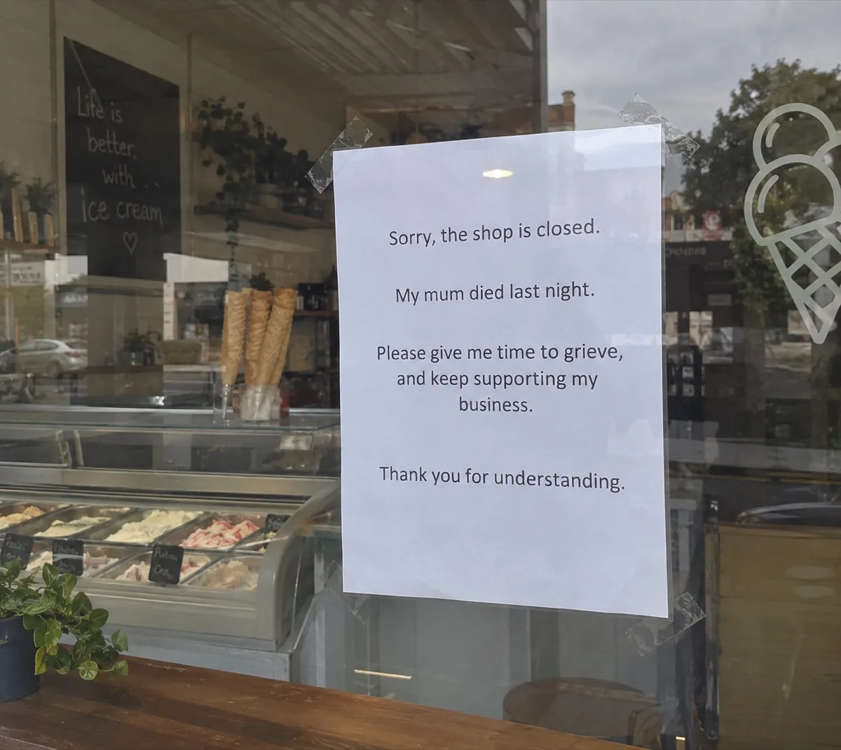 A sign taped inside the ice cream shop window reading: sorry, the shop is closed, my mum died last night, please give me time to grieve and keep supporting my business, thank you for understanding.